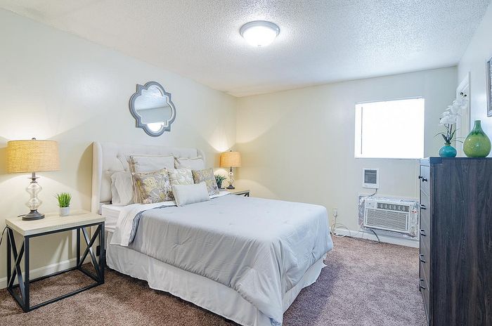 Elegant bedroom with plush bedding, stylish lamps, and a decorative mirror, offering a cozy and inviting atmosphere.