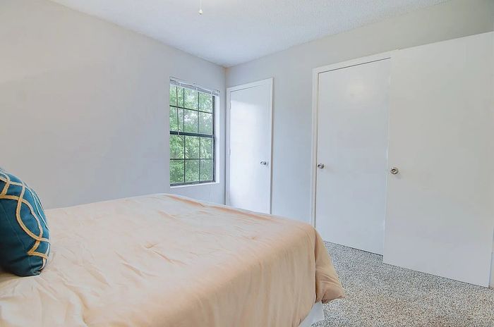 Inviting bedroom with plush bedding, natural light from large windows, and ample closet space for storage.