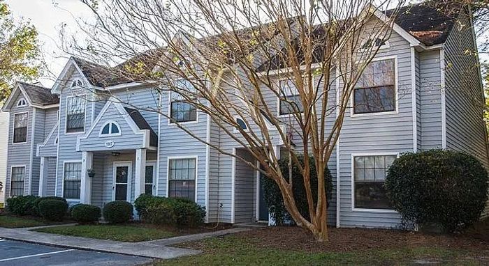 Charming townhouse exterior with classic architecture, surrounded by lush greenery and offering serene residential appeal.