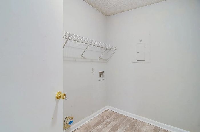 Bright utility room with modern wooden flooring and ample wall shelving, perfect for storage solutions.