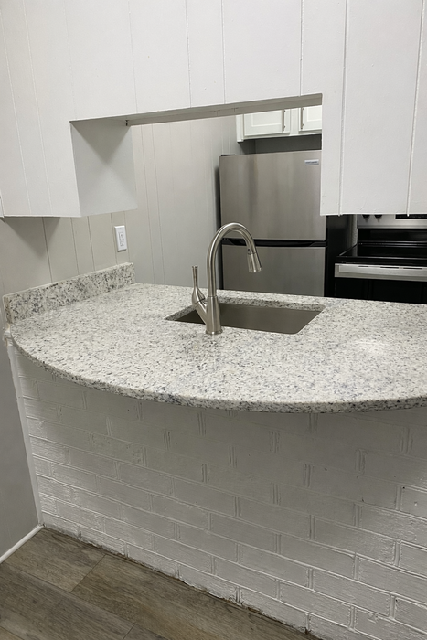 Modern kitchen with sleek stainless steel appliances and a stylish granite countertop, perfect for culinary enthusiasts.
