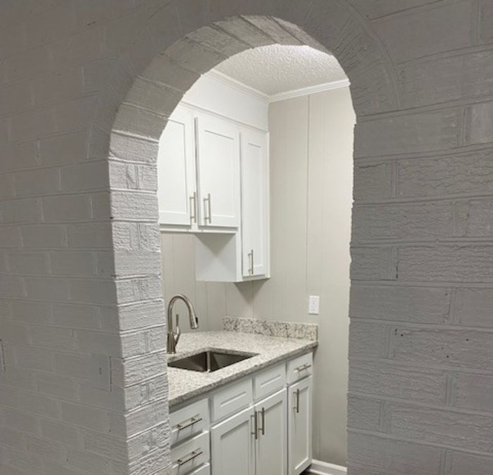 Charming kitchen with modern white cabinetry, sleek countertops, and classic archway entrance, creating a cozy and inviting space.