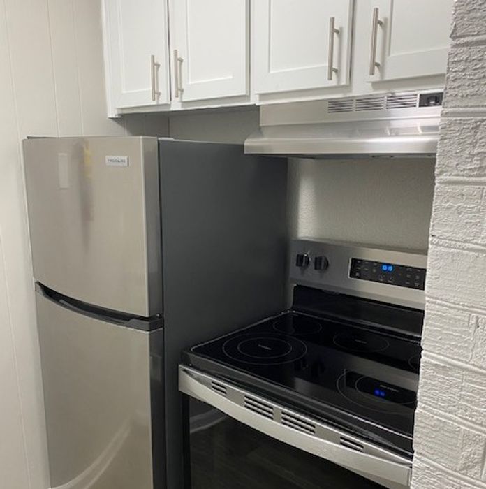Modern kitchen with sleek stainless steel appliances, including a refrigerator and a state-of-the-art electric stove, set against a backdrop of bright cabinetry.