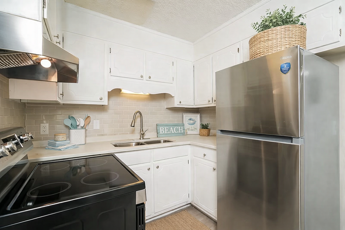 Charming kitchen with sleek stainless steel appliances, bright white cabinetry, and elegant decor for a welcoming atmosphere.