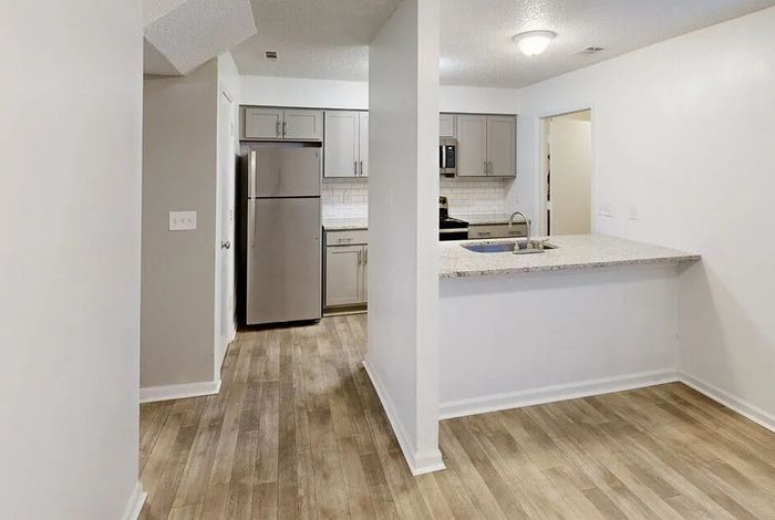 Modern open kitchen with sleek countertops, stainless steel appliances, and stylish wood flooring, perfect for contemporary living.