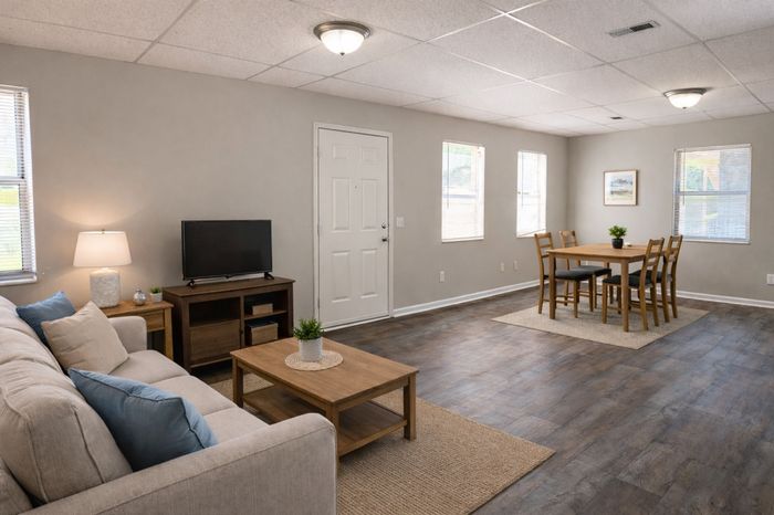 Bright and inviting living space featuring a cozy sofa, elegant wood flooring, and stylish dining area.