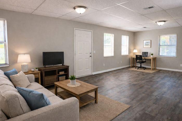 Inviting living space featuring a cozy couch, sleek TV setup, and a bright workspace with natural lighting.