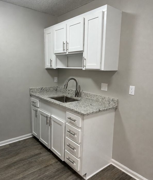 Modern kitchen nook with sleek white cabinetry, polished granite countertops, and stainless steel fixtures.
