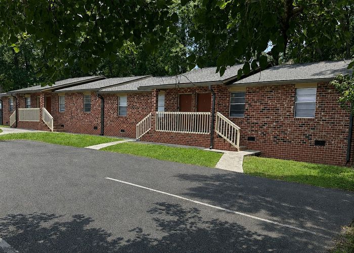 Charming brick apartment complex with lush greenery and private entrances, offering a peaceful residential atmosphere.