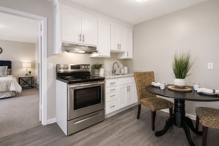 Contemporary kitchen with sleek appliances, white cabinetry, and a cozy dining nook, exuding modern charm and comfort.