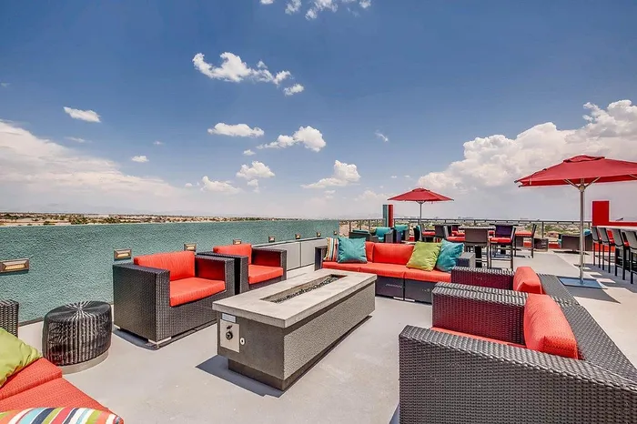 Luxurious rooftop terrace with vibrant red and green seating, modern fire pit, and panoramic sky views.