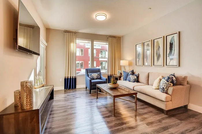Inviting living room with a modern design featuring plush beige sofa, stylish armchair, and elegant decor, complemented by large windows and warm lighting.