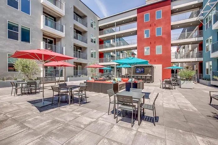 Chic apartment courtyard featuring vibrant umbrellas, cozy seating areas, and modern architecture with balconies.