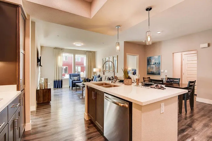 Modern open-concept living space featuring a sleek kitchen island with pendant lighting, a cozy seating area, and large windows providing natural light.