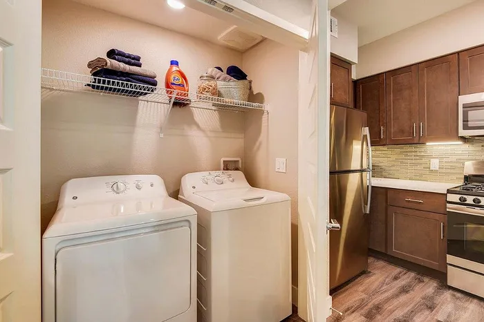 Chic apartment featuring a modern laundry area with washer and dryer beside a sleek kitchen with stainless steel appliances and stylish cabinetry.