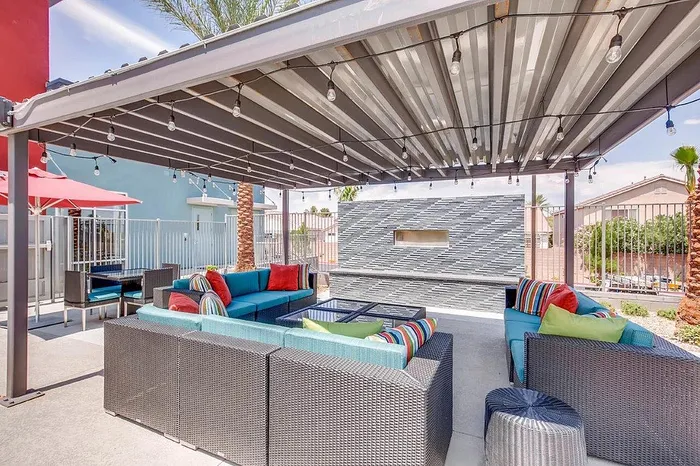 Chic outdoor patio with modern wicker furniture and vibrant cushions under a stylish pergola, perfect for entertaining.