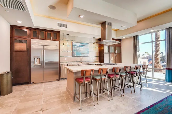 Modern kitchen with sleek stainless steel appliances, a spacious island with seating, elegant cabinetry, and large windows for natural light.