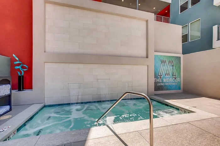 Inviting spa area with modern design, featuring elegant waterfalls and vibrant red accents at The Mercer apartments.