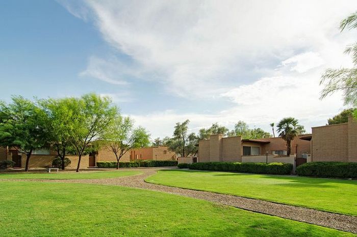 Serene residential area with lush green lawns, modern architecture, and clear blue skies.