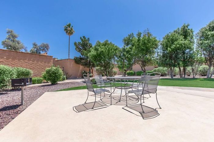 Sunny outdoor patio with stylish metal chairs and lush green lawn, perfect for relaxing and entertaining.
