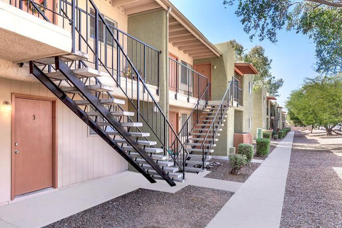 Charming apartment building exterior showcasing modern staircases, inviting front doors, lush greenery, and a well-maintained walkway.