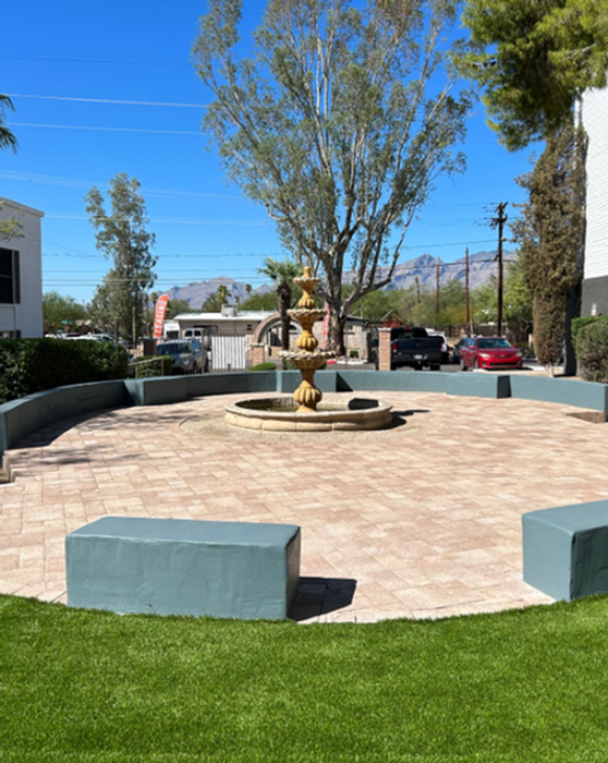 Charming outdoor plaza with central fountain, surrounded by lush greenery and offering picturesque mountain views.