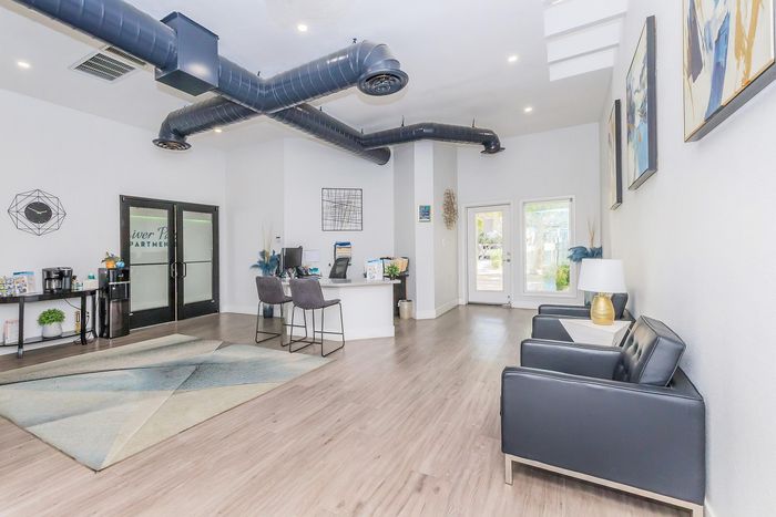 Modern apartment lobby with sleek black seating, stylish artwork, and a welcoming reception area featuring bright, natural light.