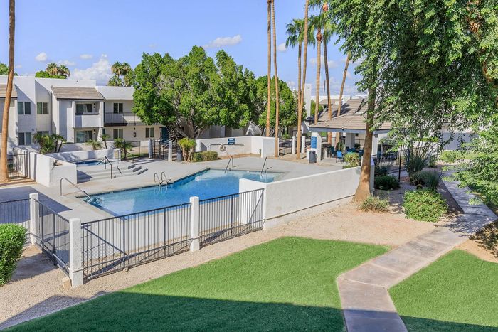 Inviting apartment complex with a sparkling outdoor pool surrounded by lush greenery and modern architecture.
