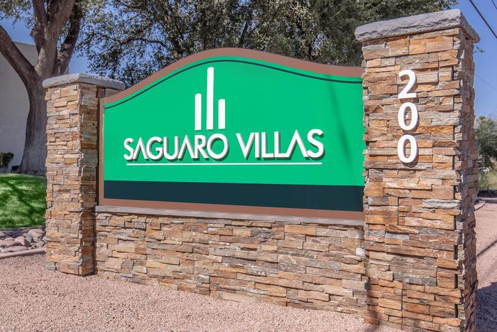 Inviting entrance sign for Saguaro Villas with attractive stonework and vibrant green backdrop, set in a lush landscape.