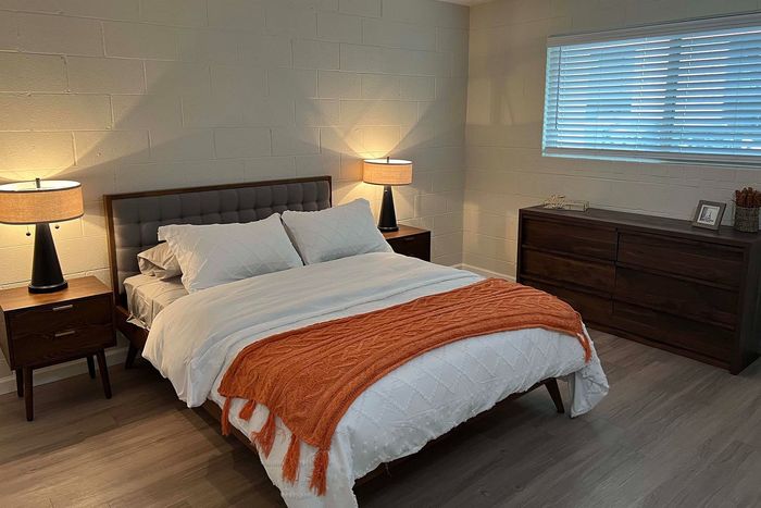 Cozy bedroom with modern furniture, featuring a plush bed, warm lighting, and elegant wood accents.
