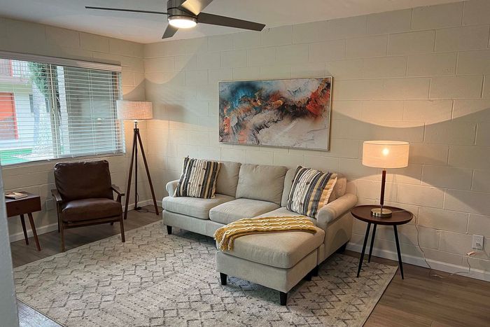 Inviting living room with cozy beige couch, abstract artwork, and warm lighting, offering a relaxing ambiance.