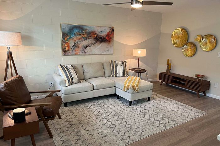 Modern living room with stylish decor, featuring a cozy gray sectional sofa, artistic wall art, and elegant accent lighting.