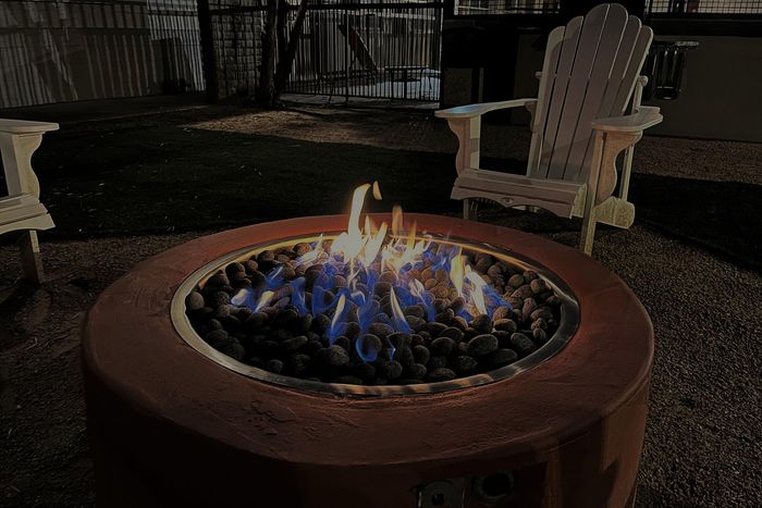 Cozy outdoor fire pit with glowing flames surrounded by stone seating in a serene nighttime backyard setting.