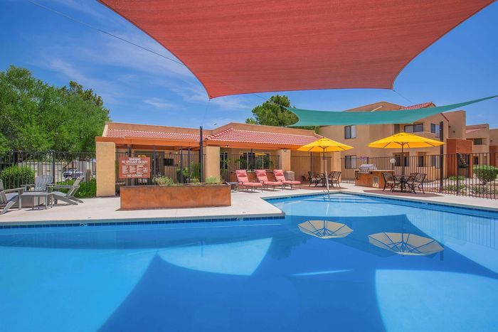 Inviting outdoor pool area with vibrant sun shades, cozy lounge chairs, and elegant patio umbrellas, ideal for relaxation and social gatherings.