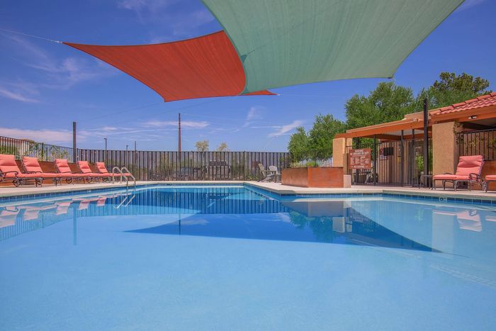 Inviting outdoor pool area with vibrant shade sails and comfortable lounge chairs, perfect for relaxation and leisure.