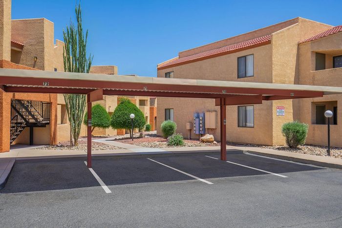 Charming apartment complex with covered parking, desert landscaping, and vibrant architectural design.