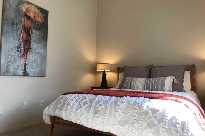 Charming bedroom with cozy bedding, accent pillows, warm lighting, and stylish artwork, creating a welcoming and serene atmosphere.