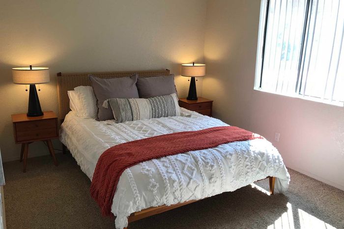 Inviting bedroom with cozy lighting, featuring a stylish bed adorned with plush pillows and a textured red throw blanket.