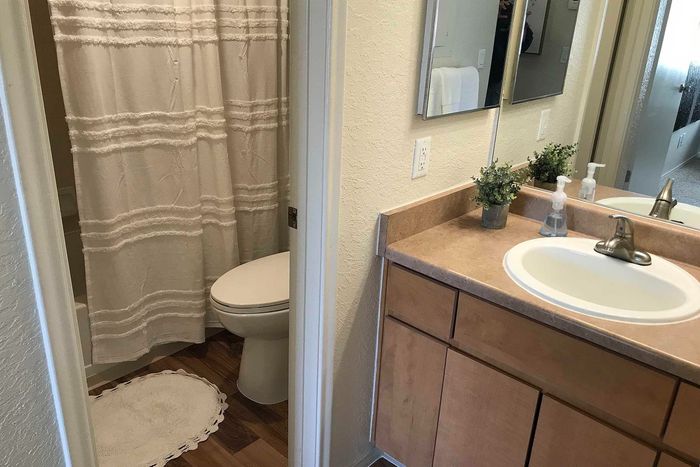 Bright and airy bathroom featuring modern fixtures, sleek wooden cabinetry, and a chic shower curtain for a cozy ambiance.