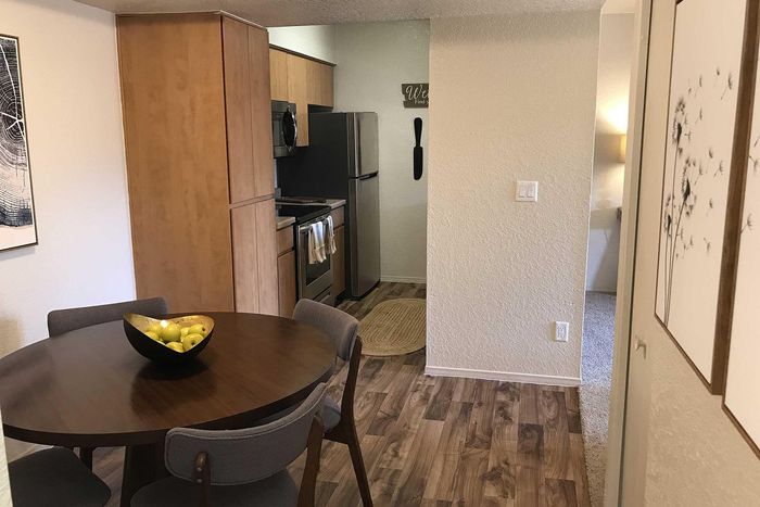 Chic dining area with a round table and modern chairs, leading into a cozy kitchen with stylish wooden cabinetry and stainless steel appliances.