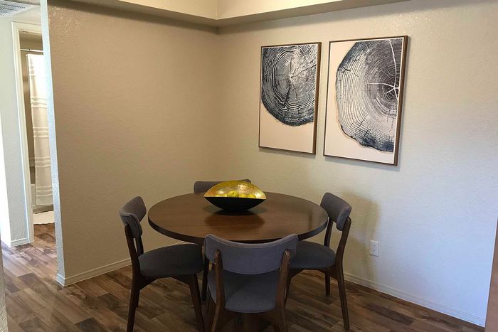 Cozy dining nook with a round wooden table, stylish gray chairs, and nature-inspired wall art adorning the neutral walls.
