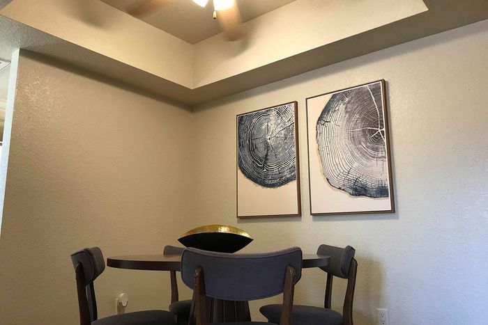 Cozy dining nook with modern artwork, featuring a round table and stylish chairs under warm lighting.