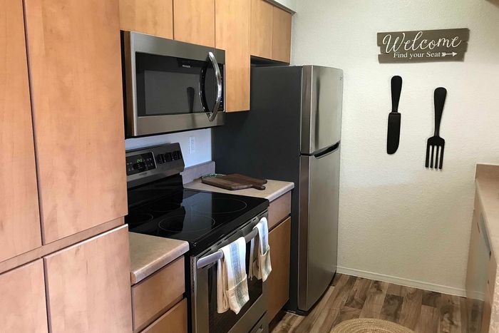 Modern kitchen with sleek stainless steel appliances, warm wooden cabinets, and charming wall decor, welcoming ambiance.