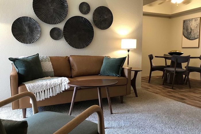 Inviting living space featuring a stylish brown leather sofa with elegant decor, modern round coffee table, and cozy dining area with chic wooden chairs.