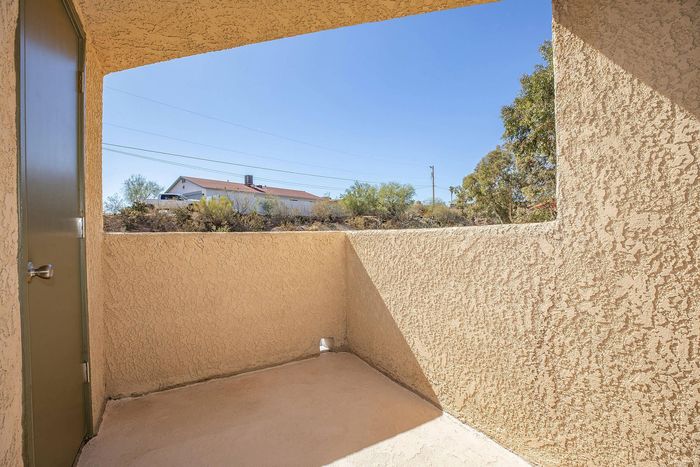 Charming sheltered patio with textured walls, offering a serene outdoor space with a peaceful view of lush greenery.