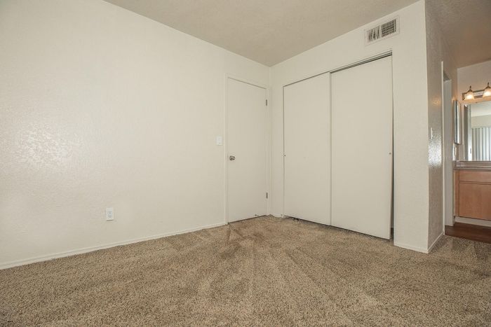 Bright and inviting bedroom with neutral walls, plush carpet, and spacious closet, perfect for creating a cozy retreat.