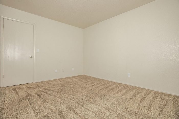 Bright, spacious room with clean carpet and a classic door, ready to be personalized and transformed into a cozy living space.