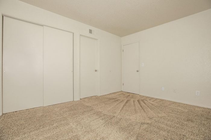Bright room featuring plush carpet flooring and minimalistic white walls, offering a modern, clean aesthetic, ideal for personal styling.