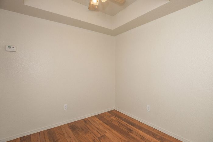 Minimalist corner view of an apartment featuring elegant hardwood flooring and a ceiling fan, offering a cozy and inviting atmosphere.