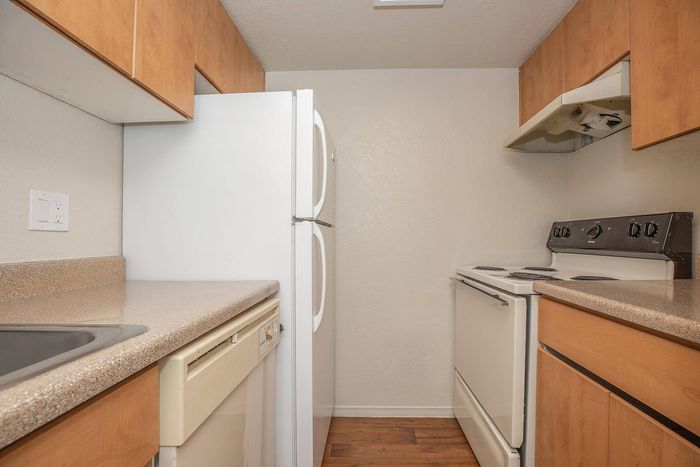Cozy kitchen with sleek countertops, wooden cabinets, and modern appliances, perfect for culinary enthusiasts.